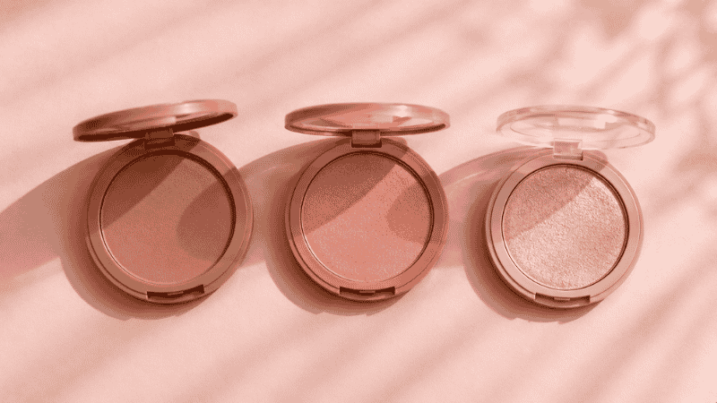 Three makeup products — bronzer, blush, and highlighter — arranged in application order