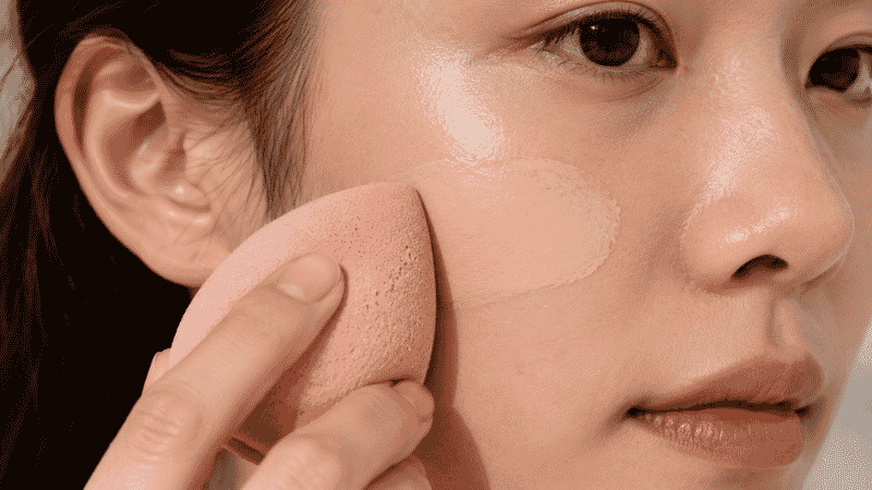 Using a damp beauty sponge to blend foundation for a natural skin finish
