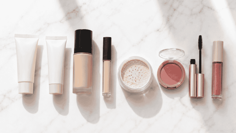 Full face makeup products laid out in application order on a white surface
