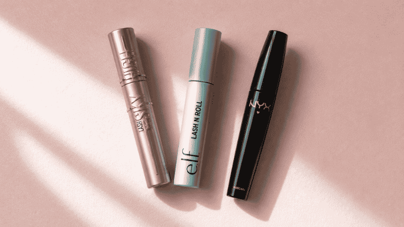 Three affordable drugstore mascara tubes arranged on a pink surface for a beginner makeup guide