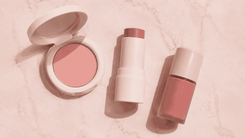 Blush brush sweeping pink powder blush on cheekbones for a natural flush