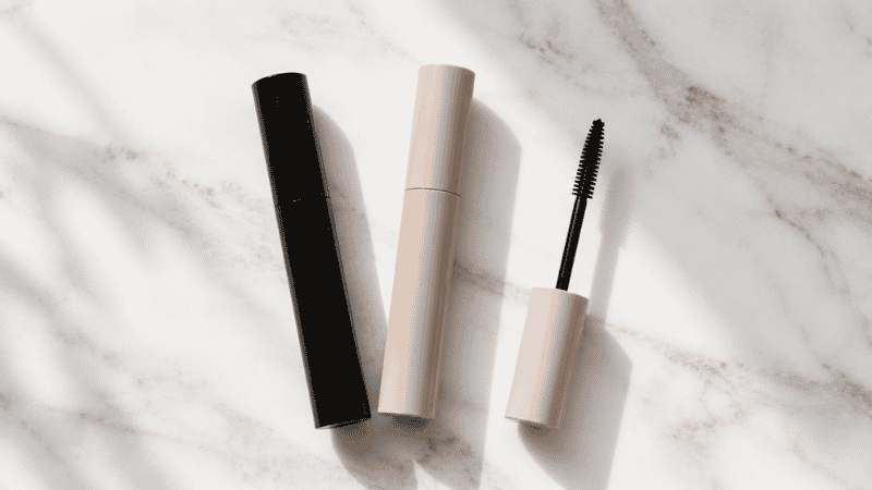 Mascara wand held close to open eye with long separated lashes showing correct application technique