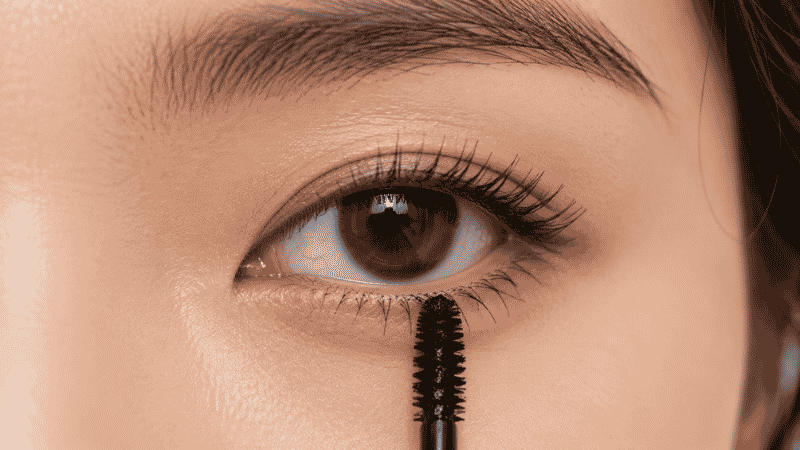 Mascara wand held vertically to apply product precisely to lower lashes without smudging