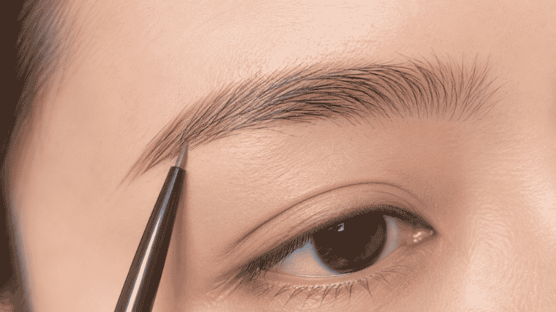Fine eyebrow pencil making short hair-like strokes through sparse brow area for a natural finish