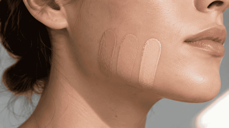Three foundation shades swatched along the jawline being checked in natural light for shade matching