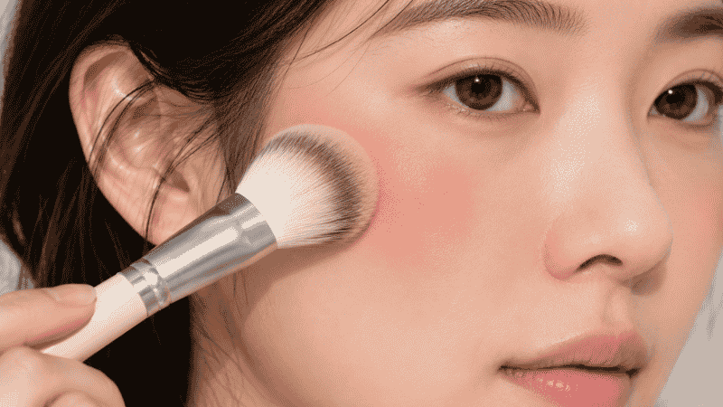 Clean fluffy brush buffing out over-applied blush on cheeks to soften the color