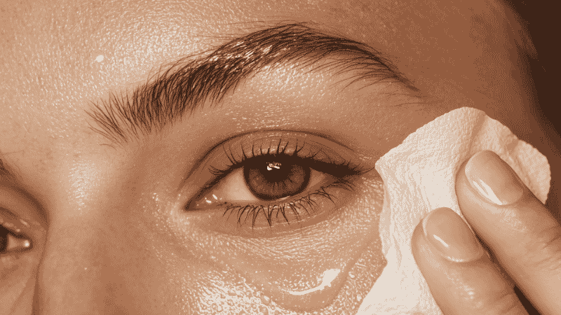 Blotting paper being pressed onto shiny skin to absorb excess oil without disturbing makeup