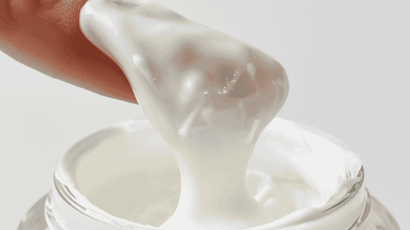 Rich ceramide moisturizing cream being scooped from a white jar showing thick nourishing texture for dry skin