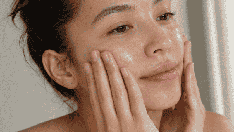 Woman applying moisturizer to clean dewy skin before natural makeup application