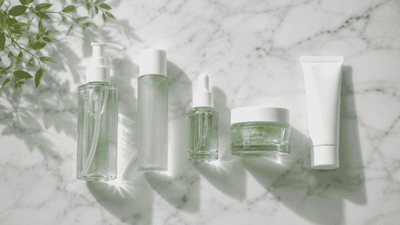 Skincare products for combination skin including gel cleanser toner serum moisturizer and sunscreen arranged on white marble