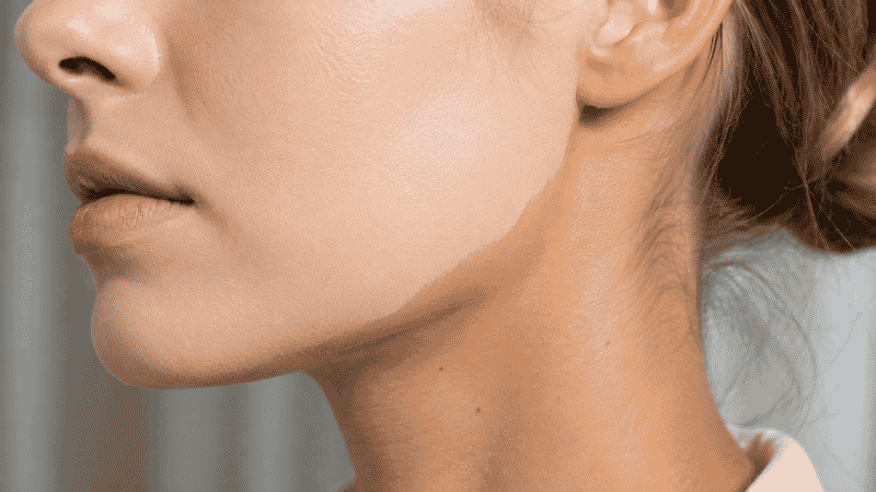Close-up of jawline showing the visible foundation line where face foundation doesn't blend into neck color