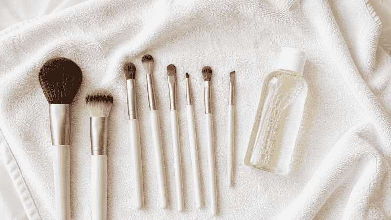 Dirty makeup brushes being cleaned with baby shampoo and water showing bristles lathering in palm of hand