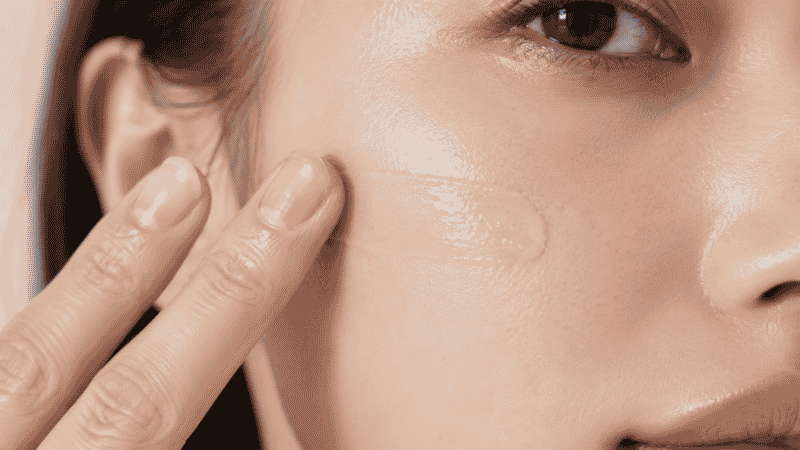 Tinted moisturizer being applied with fingers showing sheer natural skin-like coverage on cheek