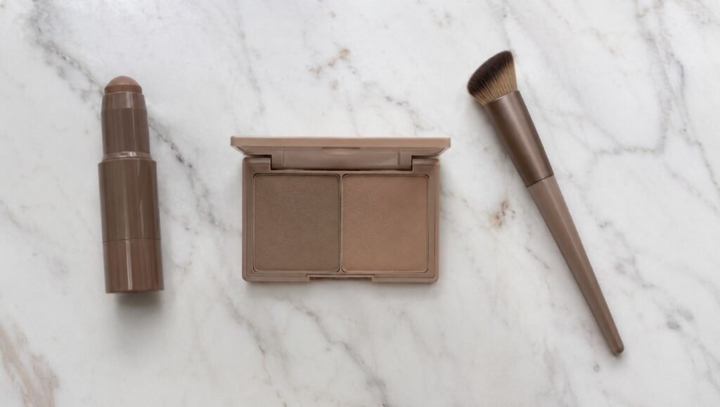 Contour stick and powder palette arranged on white marble showing drugstore contouring products for beginners
