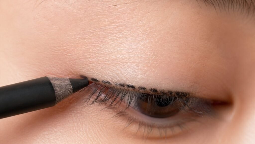Pencil eyeliner being applied in small strokes along the upper lash line close to the roots for a natural defined look